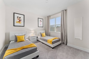 A bedroom with two beds, a nightstand, a lamp, and a window with curtains. - 3BR Pool Home Near Disney Clermont (Clermont)