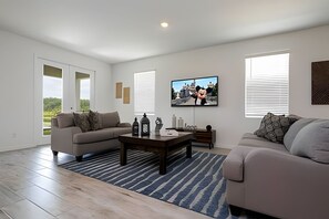 A modern living room with two sofas, a coffee table, and a TV on the wall. - 4BR West Haven Home, Lake View (Davenport)