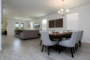 A modern dining area with a round table, six chairs, and a chandelier. - 4BR West Haven Home, Lake View (Davenport)