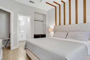 Ein modernes Schlafzimmer mit einem großen Bett, einem Nachttisch, einem Spiegel und einem Kleiderschrank.