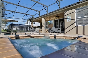 Ein Poolbereich mit Glasveranda, Sitzgelegenheiten im Freien und einem Wasserspiel.