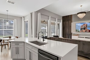 Eine moderne Küche mit einer großen Kochinsel, weißen Schränken und einem eingebauten Backofen.