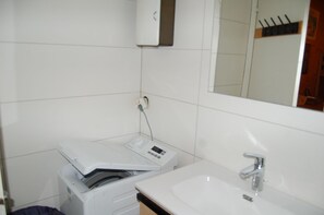 A bathroom with a white sink, a mirror, and a wall-mounted heater. - Central accommodation near the pool (Châtel)