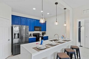 A modern kitchen with blue cabinets, stainless steel appliances, and pendant lighting. - Modern 3-bedroom at Vista Cay Resort (Orlando)