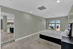 A modern bedroom with a large bed, a TV, and a view of a pool and outdoor area. - 5BR Lakeview Home w/ Pool 3min to Universal (Orlando)