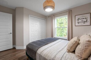 A bedroom with a bed, a window, a door, and a wall with a framed quote. - Renovated 4BR Townhome w/ Disney Game Room (Kissimmee)