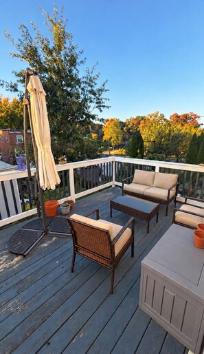 Une terrasse extérieure avec des meubles en osier, une table et un parasol.