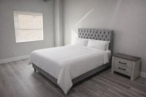 A bedroom with a bed, bedside table, and a window with blinds. - 4BR Lakefront Home w/ Dock & Private Views (Orlando)