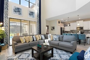 A modern living room with a grey sofa set, a coffee table, and a patterned rug. - Solterra Villa De Tommaso 5BR w Pool & Games (Davenport)