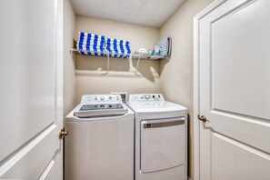 A laundry room with two washing machines and a drying rack with folded towels. - 5BR Disney Villa Pool Themed Rooms (Kissimmee)