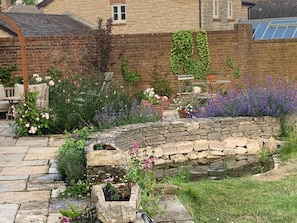 A garden with stone planters, a brick wall, and a pergola. - Cottage Sleeps 7 With Garden & Free Parking (Dorchester)