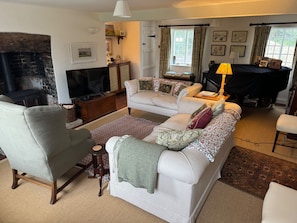 A cozy living room with a fireplace, a sofa set, a television, and a dining area. - Cottage Sleeps 7 With Garden & Free Parking (Dorchester)