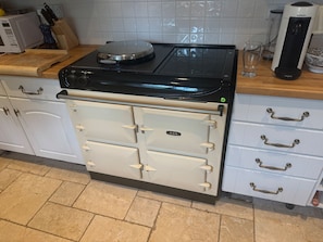 A kitchen with a black stove, white cabinets, and a tiled backsplash. - Cottage Sleeps 7 With Garden & Free Parking (Dorchester)