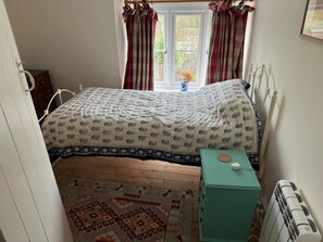 A bedroom with a bed, a radiator, a window with curtains, and a patterned rug. - Cottage Sleeps 7 With Garden & Free Parking (Dorchester)