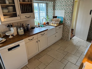 A kitchen with white cabinetry, a built-in dishwasher, a window with a view, and a tiled floor. - Cottage Sleeps 7 With Garden & Free Parking (Dorchester)