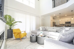 Een ruime woonkamer met een bank, fauteuils, een salontafel en een potplant.