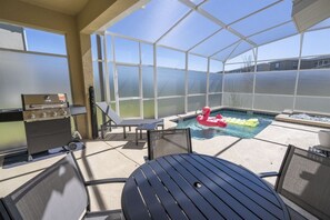 A covered outdoor area with a pool, lounge chairs, and a grill. - 5BR Villa w/ Pool & Spa at Championsgate Resort (Kissimmee)