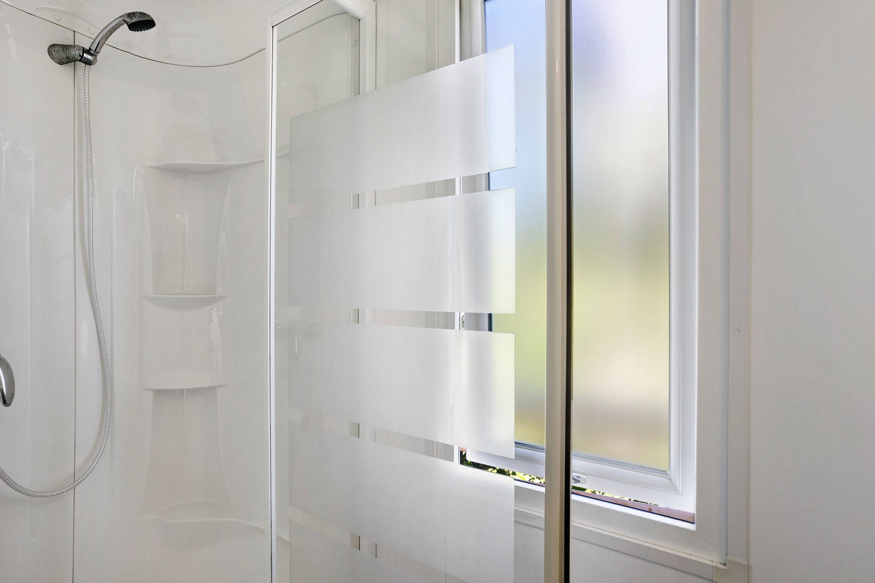 Une douche avec une porte en verre et une fenêtre.