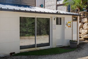 Un pequeño edificio con techo metálico, una puerta y un ventanal.