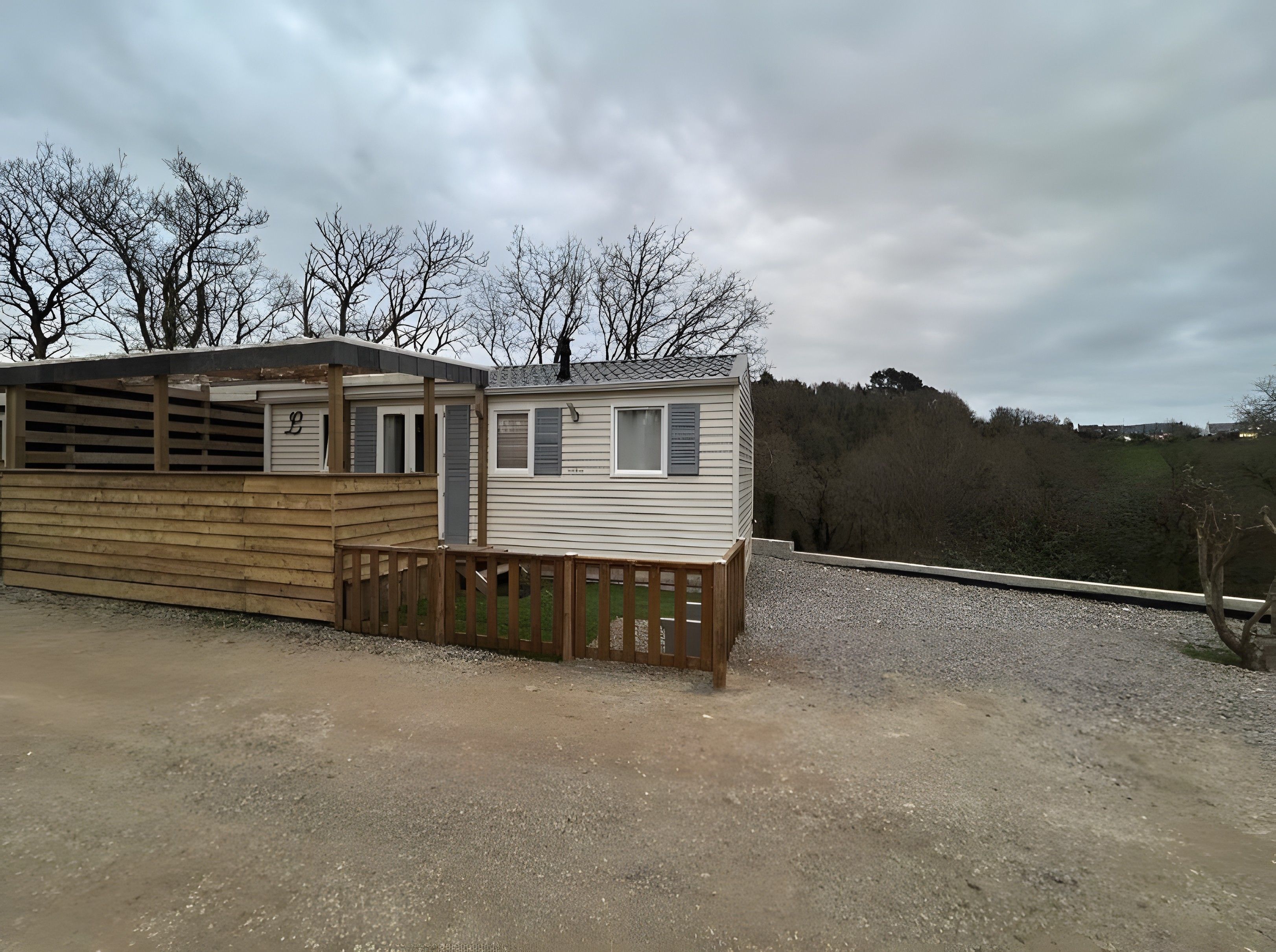 A mobile home with a fenced area and a gravel driveway.