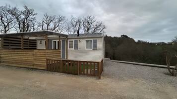 A mobile home with a fenced area and a gravel driveway.