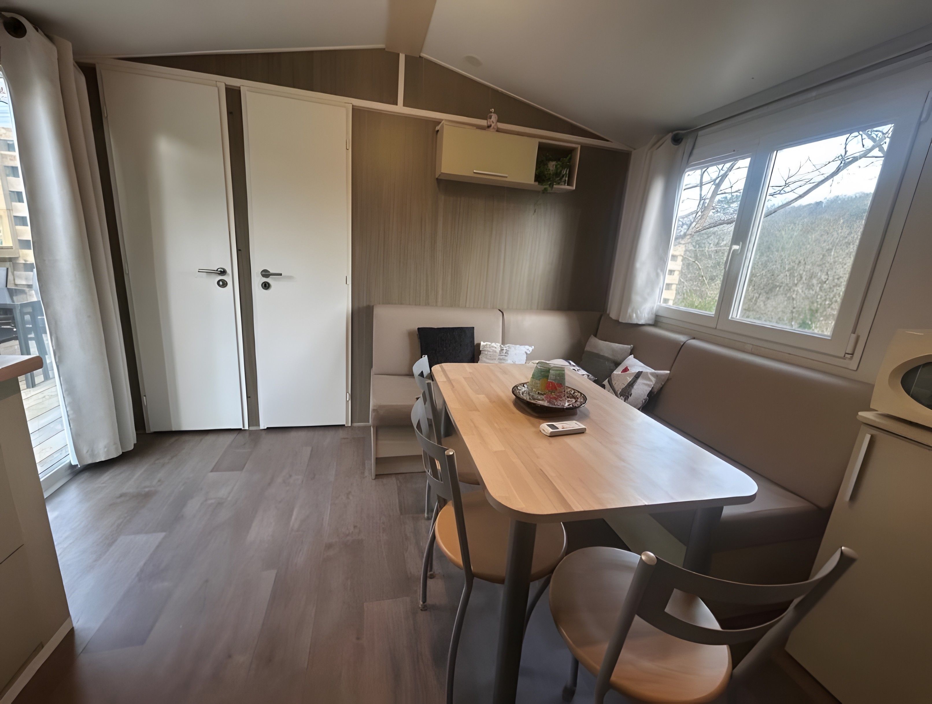 Una habitación compacta con mesa de comedor, sillas, sofá, pequeña cocina y ventana con vistas.