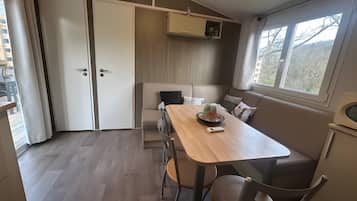 Una habitación compacta con mesa de comedor, sillas, sofá, pequeña cocina y ventana con vistas.