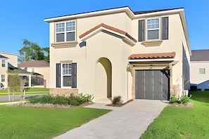 A two-story house with a garage, a front entrance with an archway, and a small front yard. - HMU - 1799 - Luxurious 7br/6ba Solara Resort (Kissimmee)