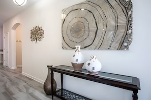 A hallway with a console table displaying two ceramic vases and a large abstract art piece on the wall. - 6BR Townhome w/ Pool 10 Min to Disney (Kissimmee)
