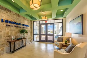 A lobby with a stone wall, a reception desk, a seating area, and a large window. - 6BR Townhome w/ Pool 10 Min to Disney (Kissimmee)