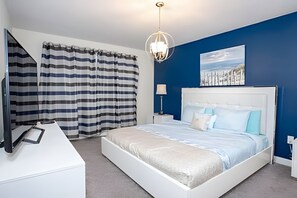 A modern bedroom with a large bed, a bedside table, a lamp, and a painting on the wall. - 6BR Townhome w/ Pool 10 Min to Disney (Kissimmee)