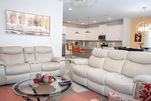 Un salon moderne avec un canapé, une table basse en verre sur laquelle sont posées des chaussures, et un tableau accroché au mur.