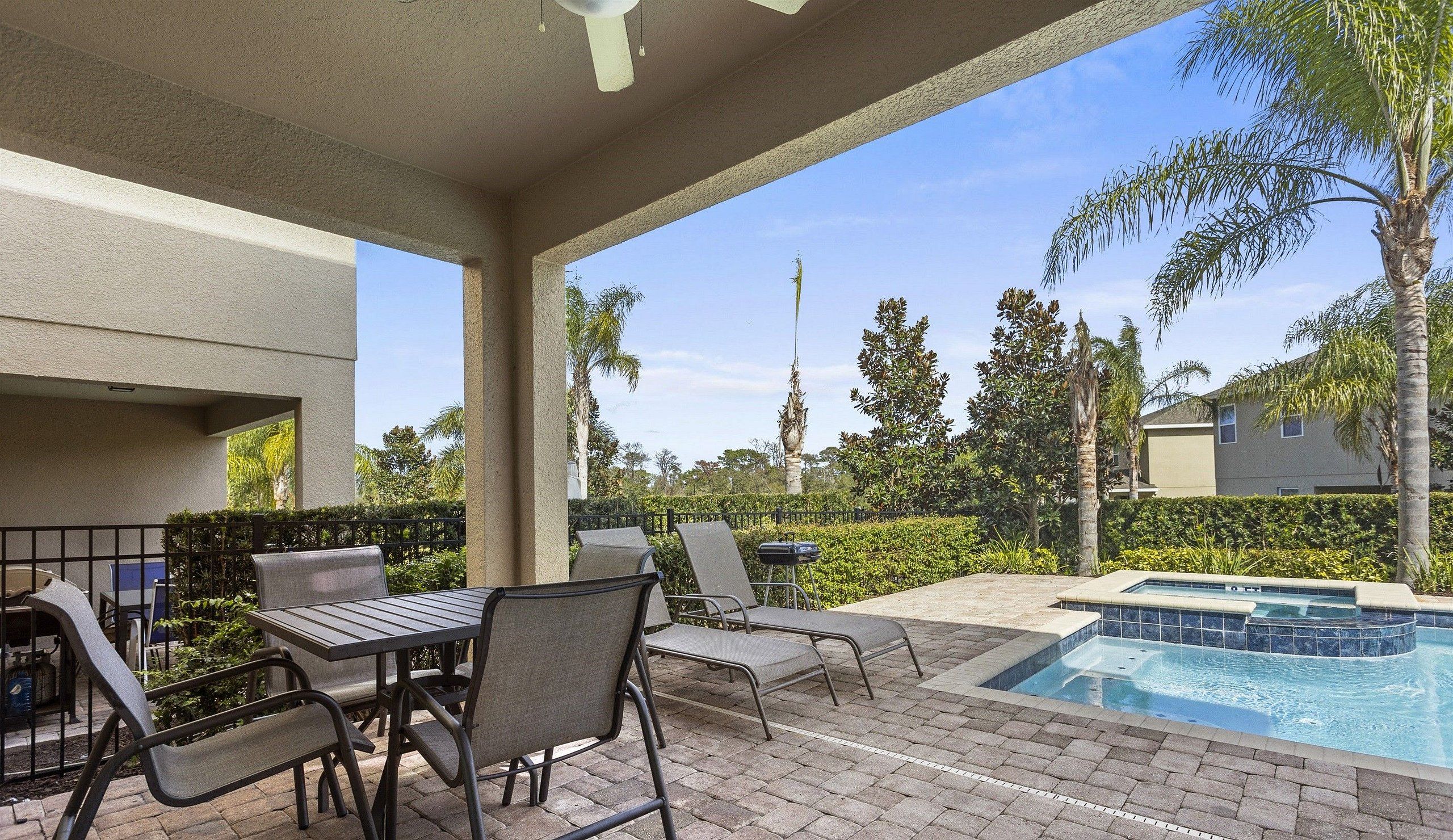 An outdoor patio area with a pool, lounge chairs, and a table.