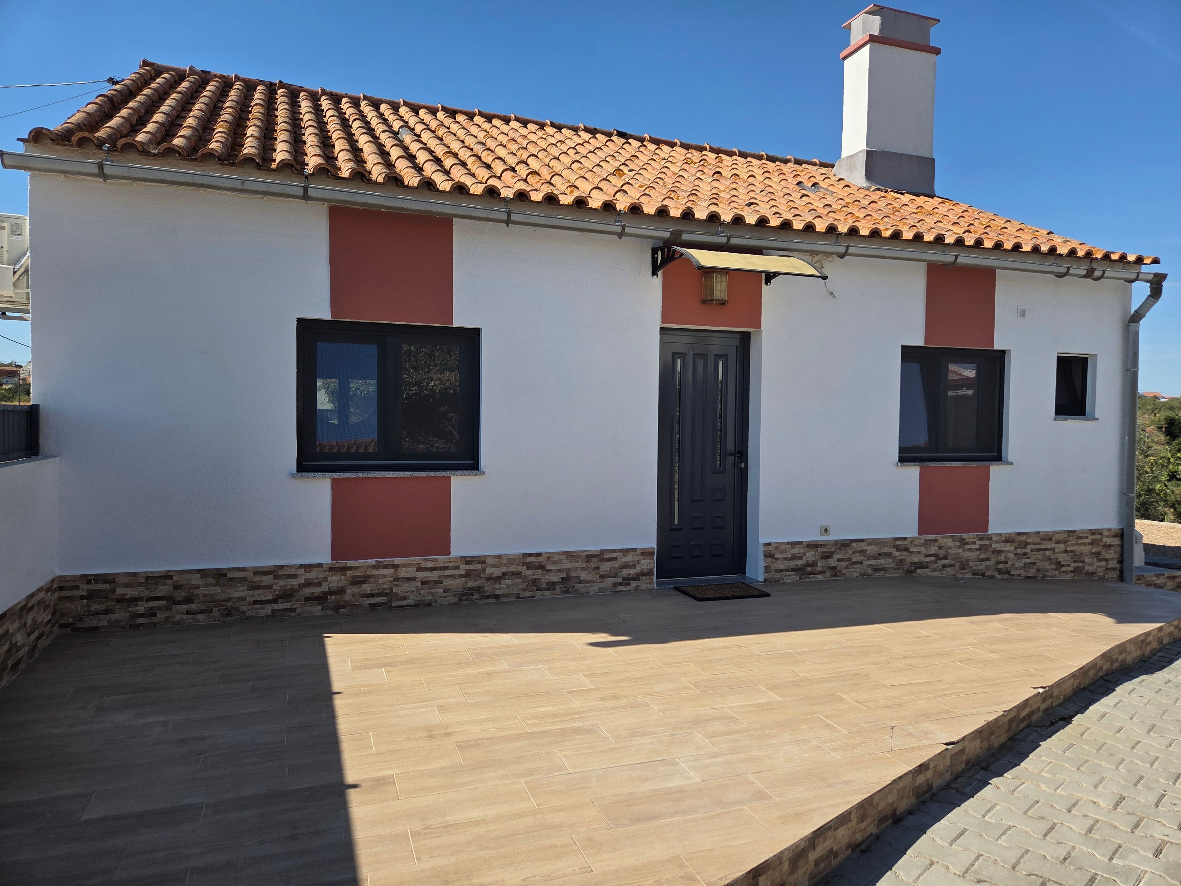 A single-story building with a tiled roof, a front door, and two windows.