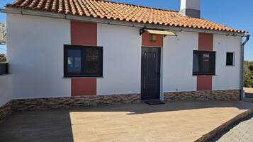 A single-story building with a tiled roof, a front door, and two windows.