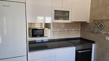 A kitchen with white cabinets, a microwave, a stove, and a dishwasher.