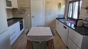 A compact kitchen with a dining table, chairs, a stove, and a sink.