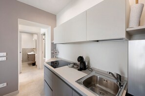 A modern kitchen with a stainless steel sink, a coffee machine, and a white cabinet above the counter.