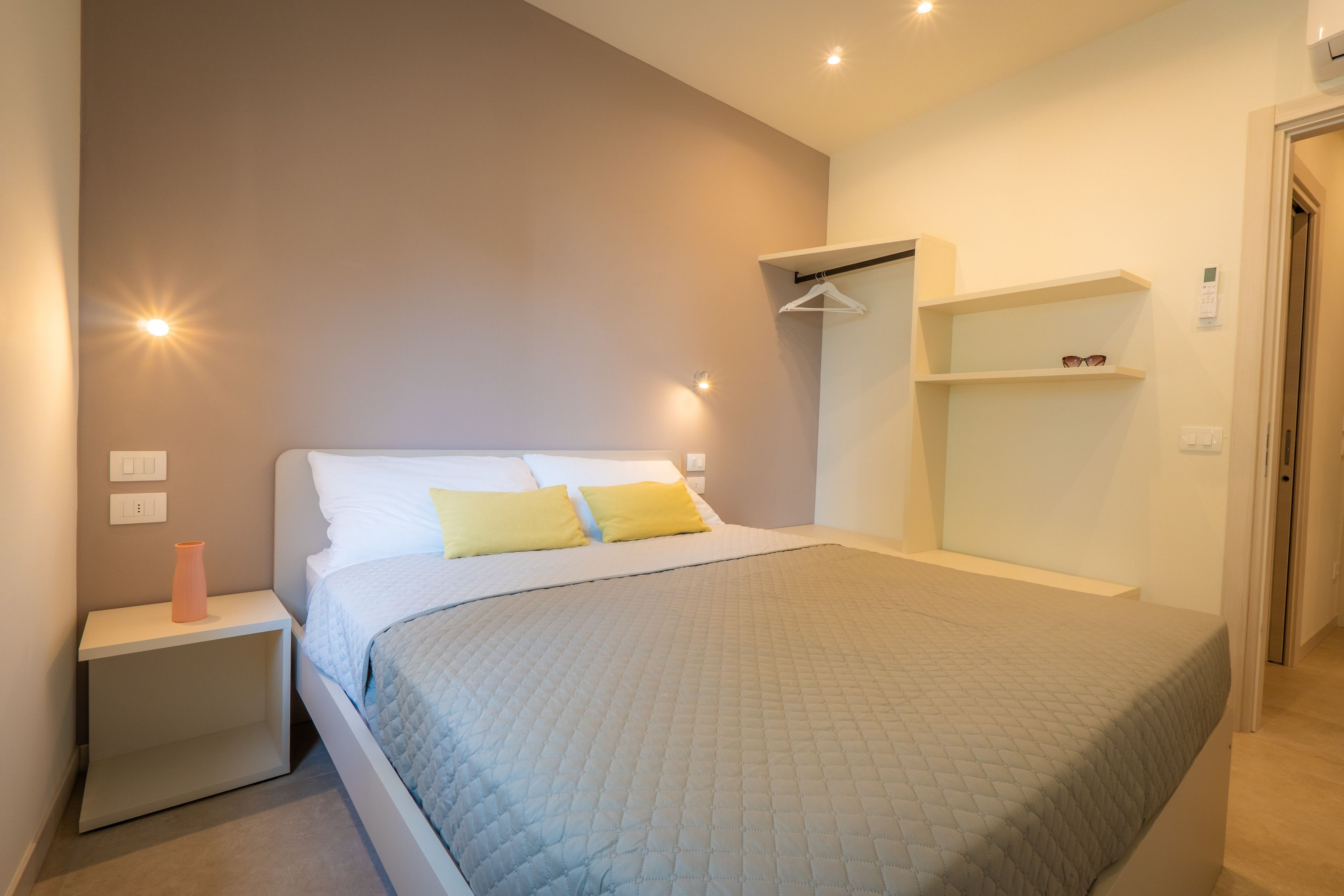 Une chambre à coucher comprenant un lit, des tables de chevet, une armoire et un luminaire suspendu.