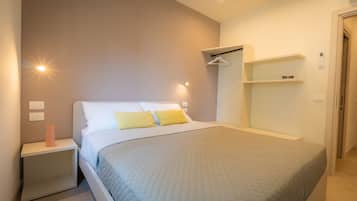 Un dormitorio con cama, mesitas de noche, armario e iluminación colgante.