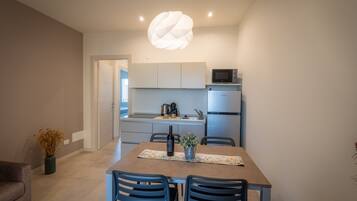 Una cocina moderna con una mesa de comedor, sillas, un microondas y un refrigerador.