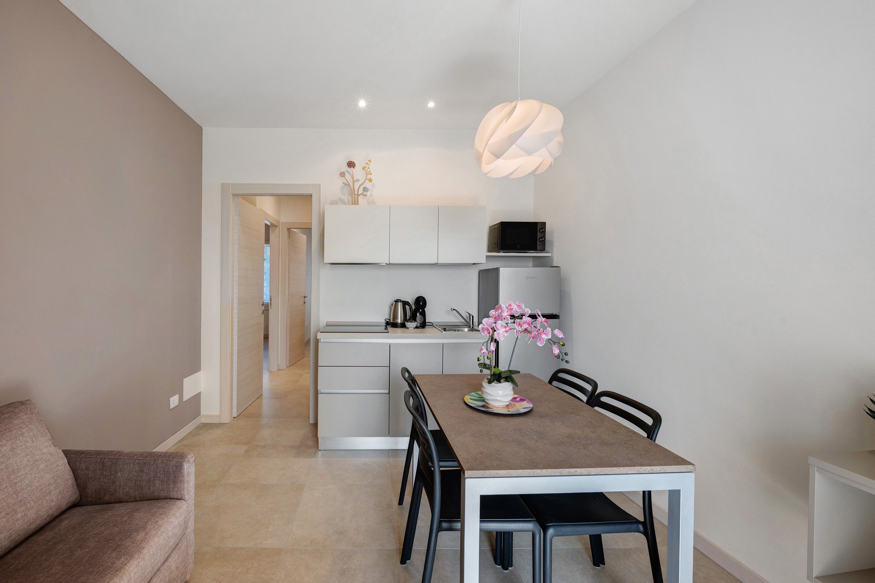 A modern kitchen with white cabinetry, a built-in microwave, and a hanging light fixture.