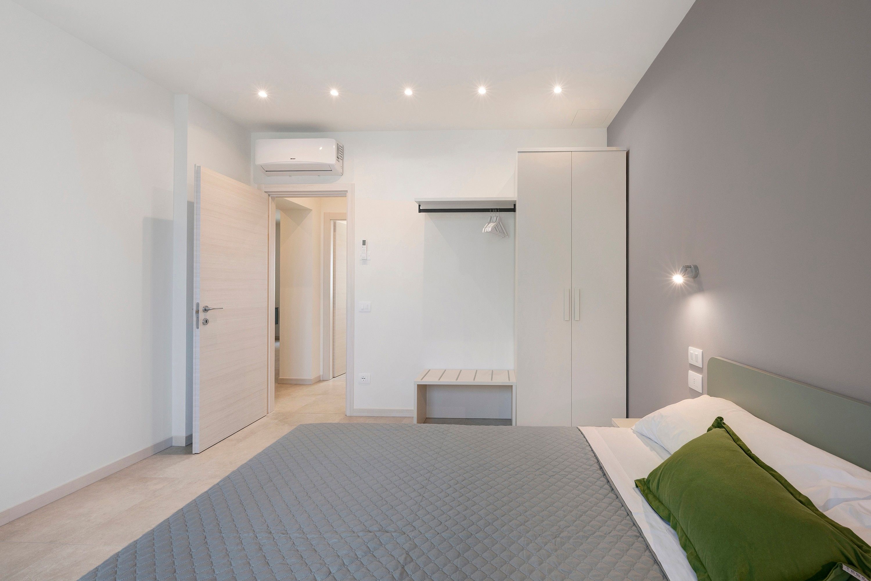 Een moderne slaapkamer met een bed, nachtkastje en inloopkast.