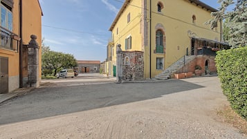Una calle con edificios, un camino de grava y coches aparcados.
