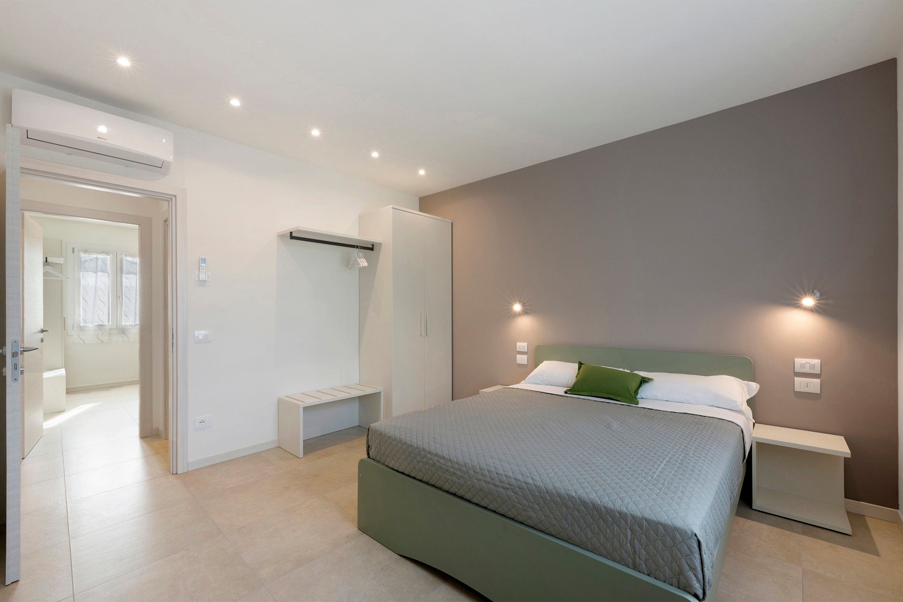 A bedroom with a bed, bedside tables, a wardrobe, and a bathroom visible through an open door.