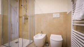 Une salle de bain avec une douche à parois de verre, un bidet et des toilettes.