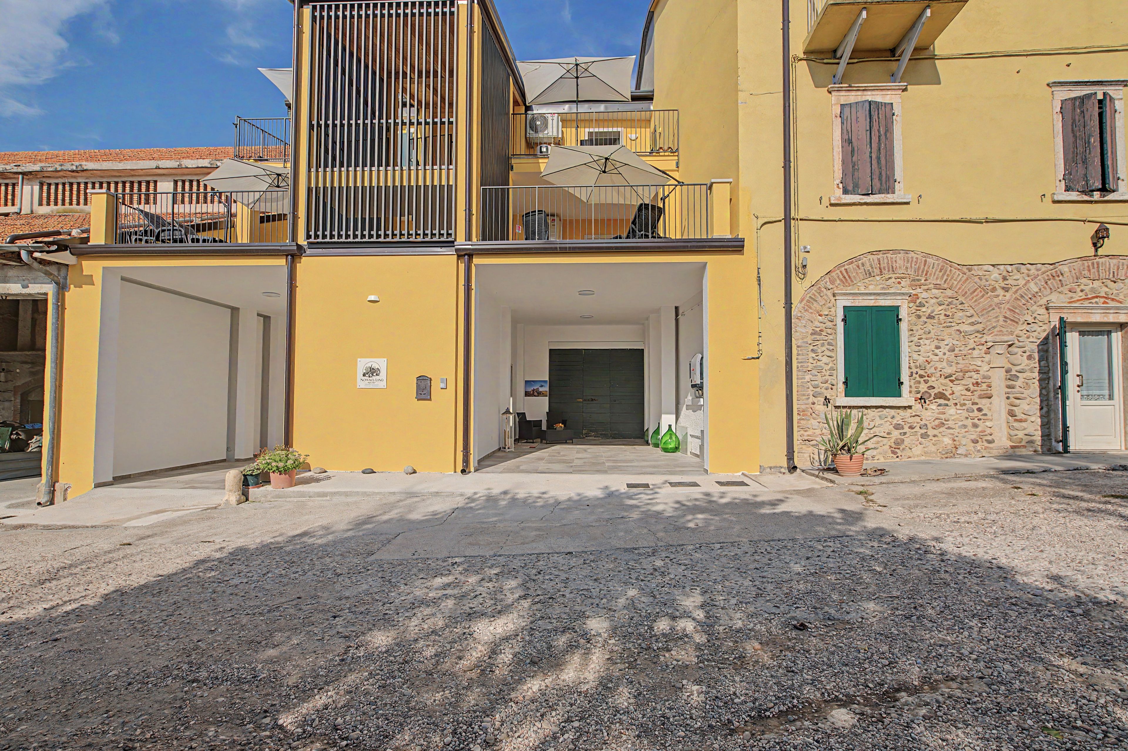 A yellow building with a gated entrance, a balcony, and a stone wall.