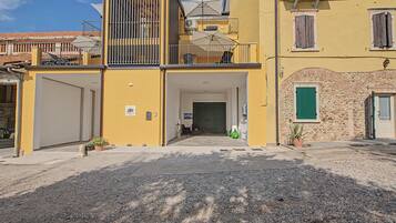 A yellow building with a gated entrance, a balcony, and a stone wall.
