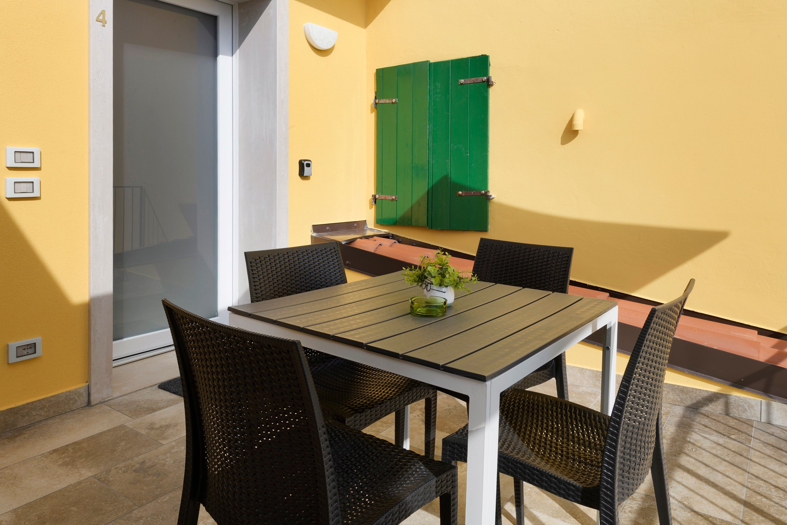 A dining area with a table and chairs, a green door, and a wall-mounted light fixture.