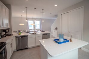 A modern kitchen with white cabinetry, stainless steel appliances, and pendant lighting. - 6BR near Disney | Pool, spa & 2 game rooms (Kissimmee)